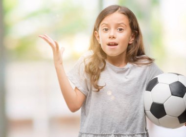 Esmer Latin kız futbol futbol topu çok mutlu ve heyecanlı, kazanan ifade büyük gülümseme ile çığlık ve ellerini kaldırdı zaferini kutluyor holding