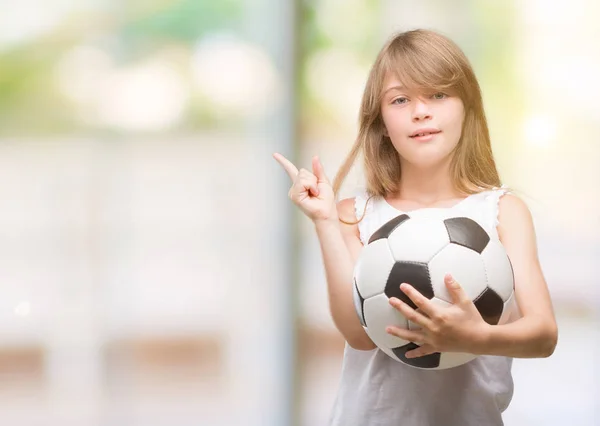 Maluch Blonde Holding Piłki Nożnej Bardzo Szczęśliwy Wskazując Dłoni Palców — Zdjęcie stockowe