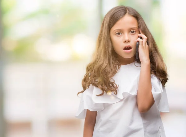 Brunette Hispanic Girl Using Smartphone Scared Shock Surprise Face Afraid — Stock Photo, Image