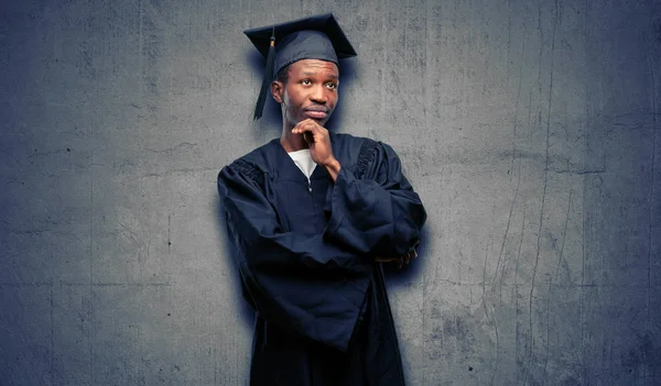 Молодой Африканский Аспирант Чернокожий Мужчина Думает Смотрит Вверх Выражая Сомнения — стоковое фото