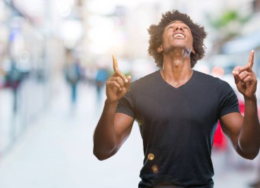 Afro Amerikalı adam izole arka plan üzerinden hayran ve yukarıya bakıp parmakları ile işaret şaşırttı ve silah kaldırdı.