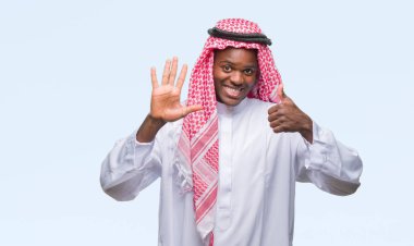 Geleneksel keffiyeh gösterilen ve parmakları ile işaret izole arka plan üzerinde giyen genç Arapça Afrika adam kendinden emin ve mutlu gülümseyerek süre 6 numara.