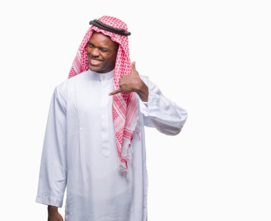 Geleneksel keffiyeh yapıyor gülümseyen izole arka plan üzerinde giyen genç Arapça Afrika adam telefon hareketi ile el ve parmak telefonda konuşuyor gibi. Kavramları iletişim.
