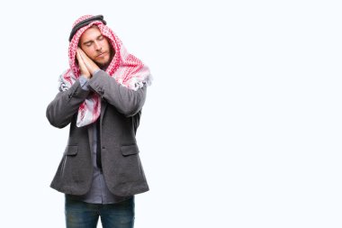 Uzun saçlı keffiyeh uyku yorgun hayal ve ellerle birlikte poz ile kapalı gözler gülümseyen izole arka plan üzerinde giyen genç Arap yakışıklı.