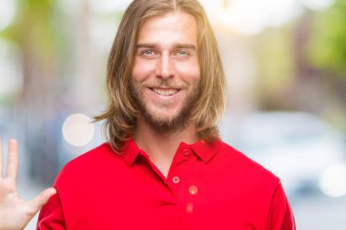 Gösterilen ve parmakları ile işaret izole arka plan üzerinde uzun saçlı Genç yakışıklı adam kendinden emin ve mutlu gülümseyerek süre beş numara.