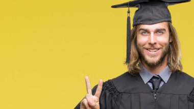 Gösterilen ve parmakları ile işaret izole arka plan üzerinde uzun saçlı Genç mezun yakışıklı ikincisi ise kendinden emin ve mutlu gülümseyerek.