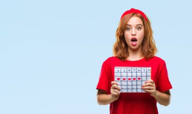 İzole arka plan adet takvim bir sürpriz yüz, korkuyor ve heyecanlı korku ifadesi ile şok korkmuş tutan genç güzel kadın