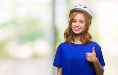 Genç güzel kadın hareketi el ile mutlu yaşasın yapıyor izole arka plan üzerinde bisikletçi kask giyiyor. Kameraya bakarak başarı gösteren ile ifade onaylama.