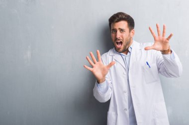 Profesyonel yakışıklı genç gri grunge üzerinde duvar giyen beyaz önlük korkuyor ve korku ifade dur hareketi el ile ile dehşete şokta bağırarak. Panik kavramı.