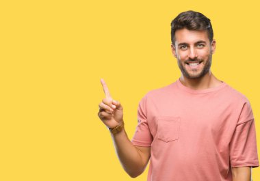 Kameraya bakarak yan el ve parmak ile işaret eden genç yakışıklı adam yüzünde kocaman bir gülümseme ile izole arka plan üzerinde.