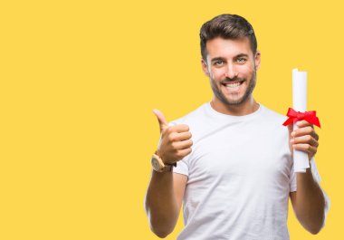 Yakışıklı delikanlı izole arka plan üzerinde derecesi büyük gülümseme ok işareti, başparmak ile parmak, mükemmel işareti yapıyor ile mutlu holding