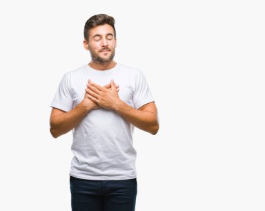 Yakışıklı delikanlı ile gülümseyen izole arka plan üzerinde kapalı gözler ve yüzünde minnettar jest ile göğüs üzerinde eller. Sağlık kavramı.