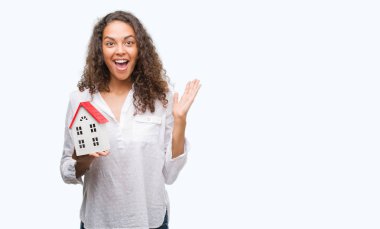 Yazlık çok mutlu ve heyecanlı, kazanan ifade ile çığlık zaferini kutluyor büyük tutan genç İspanyol gerçek durum Aracısı kadın gülümse ve el kaldırdı