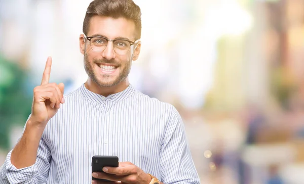 年轻英俊的人发短信使用智能手机在孤立的背景下惊讶的想法或问题指着一个快乐的脸 — 图库照片