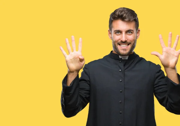 Young catholic christian priest man over isolated background showing and pointing up with fingers number nine while smiling confident and happy.