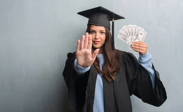 Joven Morena Sobre Pared Gris Grunge Con Uniforme Graduado Sosteniendo — Foto de Stock