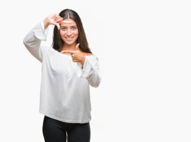 Genç güzel Arap kadın elle yapma çerçeve ve parmakları ile mutlu yüz gülümseyen izole arka plan yüzünden. Yaratıcılık ve Fotoğrafçılık kavramı.