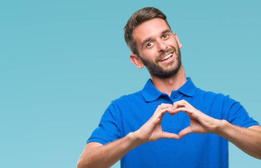 Yakışıklı delikanlı aşık kalp simgesi ve elleriyle şekil gösteren gülümseyen izole arka plan üzerinde. Romantik kavramı.