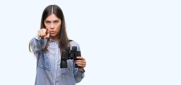 年轻的西班牙裔妇女手持望远镜指向相机和你 正面和自信的手势从前面 — 图库照片