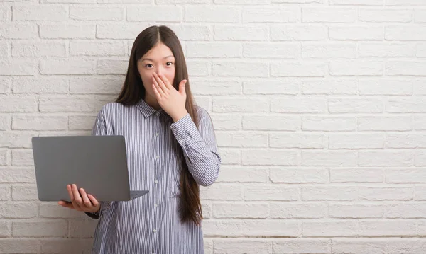 沈黙の中 秘密の概念で怖がっている恐怖の表現の間違い恥とショックを受けた手でノート パソコン カバー口を使用してレンガの壁を越えて若い中国の女性 — ストック写真