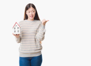 Genç gerçek durum Aracısı kadın işaret ve başparmak kadar mutlu yüz gülümseyen tarafı ile gösterilen arka plan holding ev izole Çin