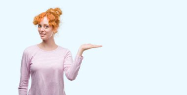Genç Kızıl saçlı kadın gülümseyen neşeli sunulması ve kameraya bakarak avucunun ile işaret.