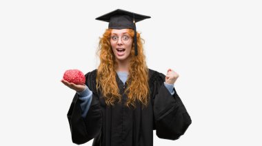 Duygu tezahürat Tekdüzen gurur çığlık beyin tutarak ve zafer ve başarı çok heyecanlı, kutluyor giyen genç redhead öğrenci kadın mezun