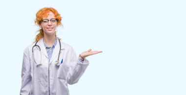 Neşeli sunulması ve kameraya bakarak avucunun ile işaret gülümseyen Doktor üniforması giyen genç Kızıl saçlı kadın.