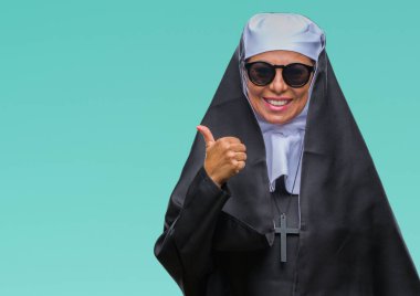 Orta yaş üst düzey Katolik Rahibe kadın hareketi el ile mutlu yaşasın yapıyor izole arka plan üzerinde güneş gözlüğü takıyor. Kameraya bakarak başarı gösteren ile ifade onaylama.