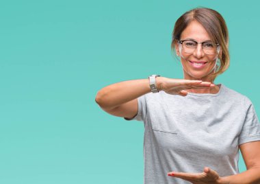 Arka plan ile büyük ve büyük boy işaret, ölçü birimi sembol gösteren el eller üzerinde gözlük takan orta yaş İspanyol kadın kıdemli izole. Kameraya bakarak gülümsüyordu. Ölçüm kavramı.