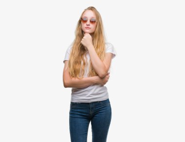 Güneş gözlüğü ciddi bir yüz düşünme hakkında soru, çok karışık fikir giymiş sarışın genç kadın