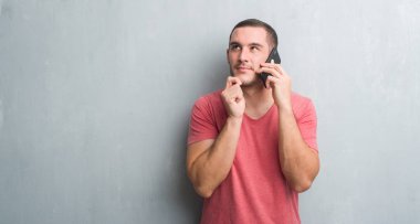 Telefon ciddi bir yüz düşünme hakkında soru, çok karışık fikir söz gri grunge duvarın üzerinden beyaz delikanlı