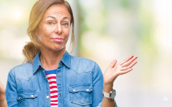 Orta yaş üst düzey İspanyol kadın izole arka plan clueless ve şaşkın bir ifadeyle kollar ve eller kaldırdı. Şüphe kavramı.