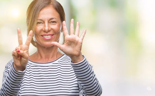 中年资深西班牙裔妇女在孤立的背景显示和指向手指数七 而微笑着自信和快乐 — 图库照片