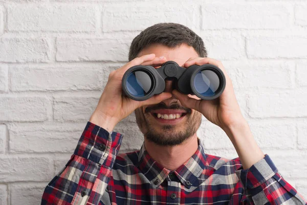 Homem Adulto Jovem Sobre Parede Tijolo Olhando Através Binóculos Com — Fotografia de Stock