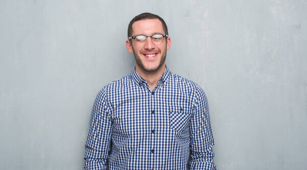 Young caucasian business man over grey grunge wall with a happy face standing and smiling with a confident smile showing teeth