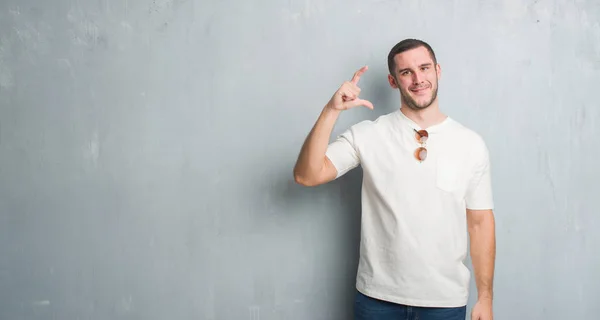 Kaukasische Jongeman Grijs Grunge Muur Dragen Zonnebril Glimlachen Vertrouwen Gebaren — Stockfoto