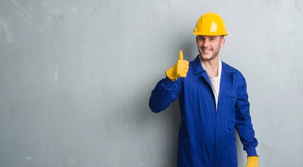 Homem Caucasiano Jovem Sobre Parede Grunge Cinza Vestindo Uniforme Empreiteiro — Fotografia de Stock