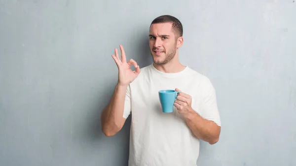 Giovane Uomo Caucasico Sopra Grigio Grunge Muro Driking Una Tazza — Foto Stock