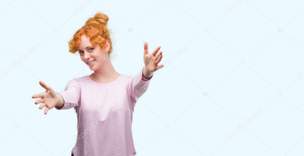 Young redhead woman looking at the camera smiling with open arms for hug. Cheerful expression embracing happiness.