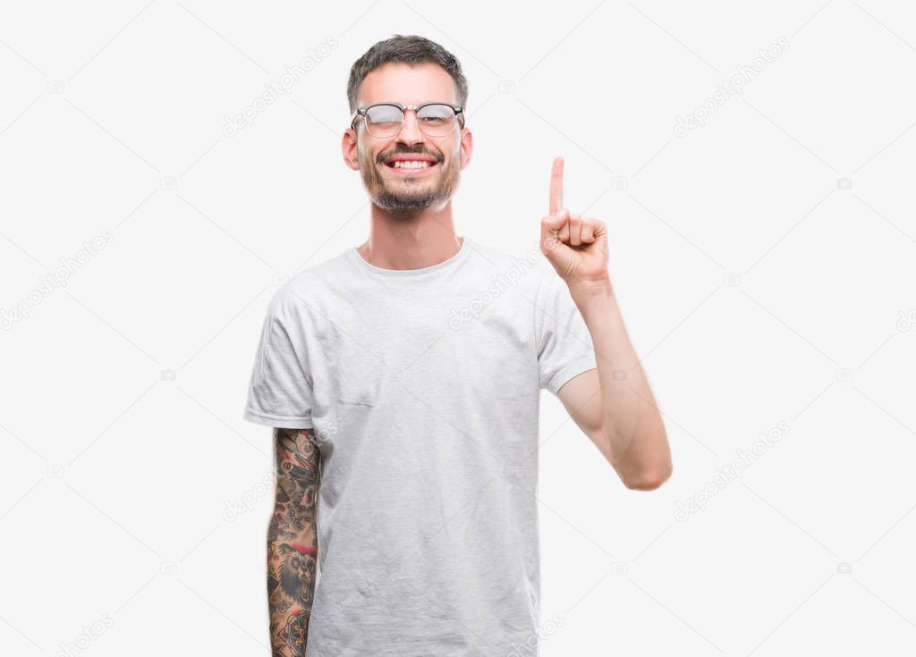 Young tattooed adult man showing and pointing up with finger number one while smiling confident and happy.
