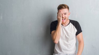 Gri grunge duvar kaplama el yüz ve sürpriz duygu kendinden emin gülümseme ile tek gözlü genç Kızıl saçlı adam.