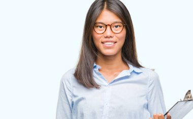 İzole arka plan ayakta ve diş gösterilen kendine güvenen bir gülümsemeyle gülümseyerek mutlu bir yüz ile pano tutan genç Asya iş kadın