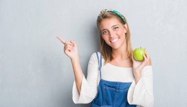 Grunge güzel genç kadın gri yeşil elma el ve parmak ile tarafına işaret çok mutlu yemek duvar