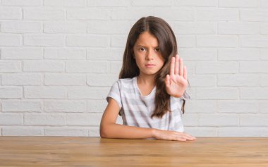 Evde masaya oturan genç İspanyol çocuğun elin avuç ile şarkı stop yapıyor. Negatif ve ciddi bir jest yüz ifadesiyle uyarı.