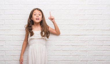 Beyaz tuğla genç İspanyol çocuk başarılı fikirle işaret parmağı duvar. Çıktıktan ve mutlu. Bir numara.