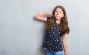 Üzerinde gri duvar grunge gülümseyen genç İspanyol çocuğun el ve parmak telefonda konuşmak ile telefon jest yapıyor. Kavramları iletişim.