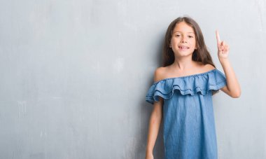 Genç İspanyol çocuk için gösterilen ve kendinden emin ve mutlu gülümseyen bir parmak ile işaret eden oktan yukarı grunge gri duvar.