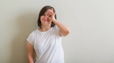 Down sendromu kadın gülümsüyor, parmakları ile mutlu yüz üzerinden seyir göz el ile ok jest yapıyor duvarın üzerinden ayakta.