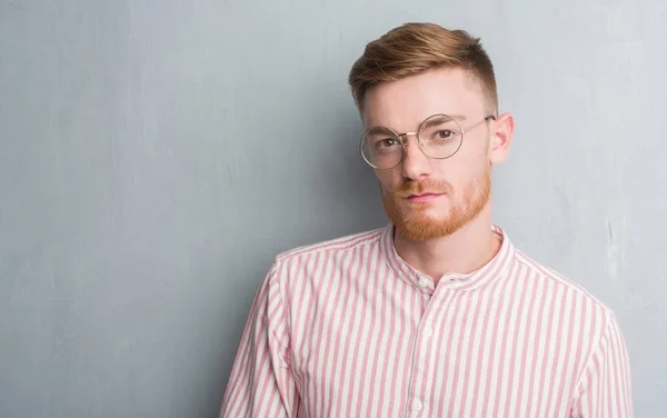 Joven Pelirrojo Hombre Sobre Gris Grunge Pared Con Una Expresión —  Fotos de Stock